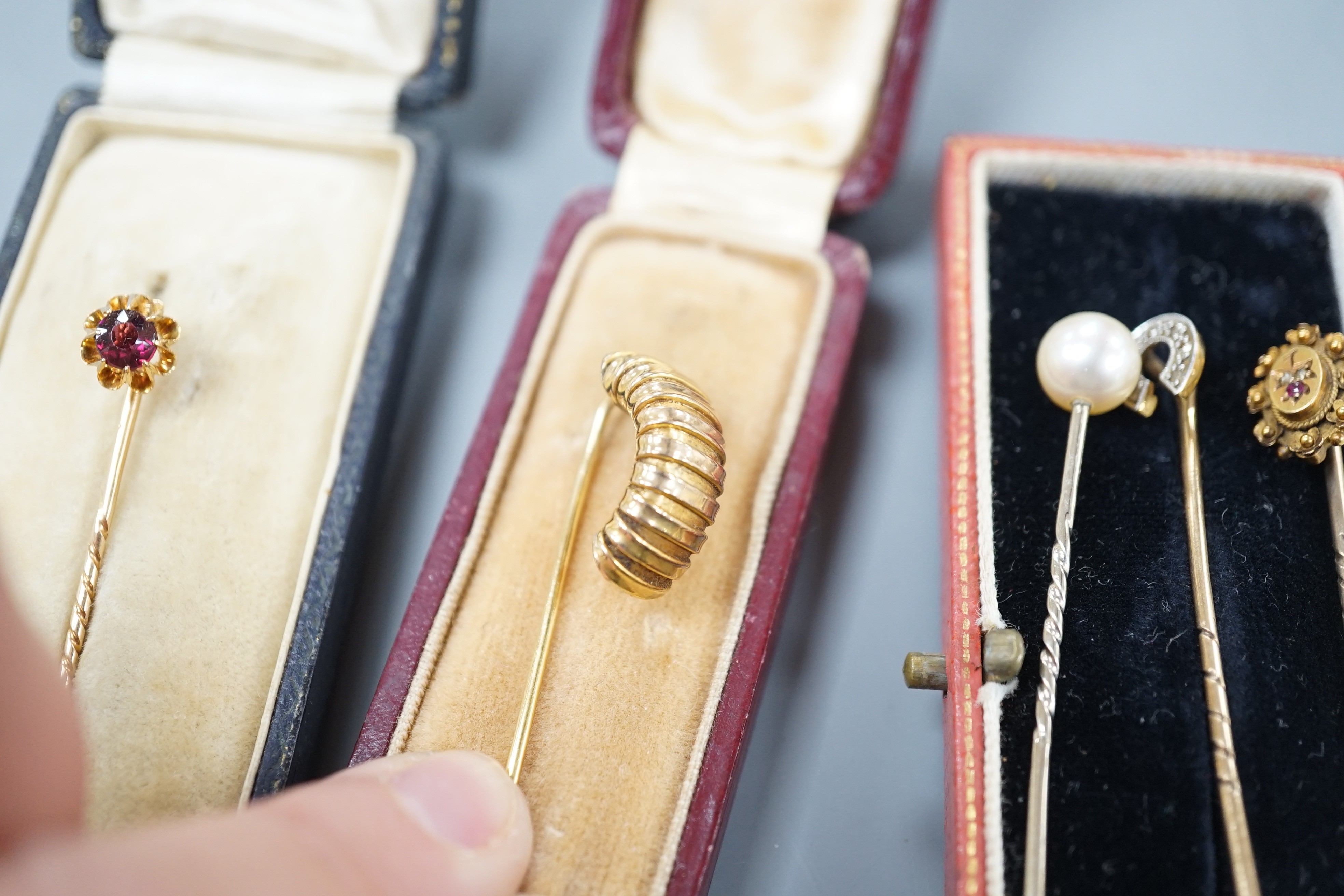 Three assorted early to mid 20th century yellow metal and gem set stick pins including diamond chip set horseshoe, 57mm and 15ct ruby and diamond chip and two other stick pins.